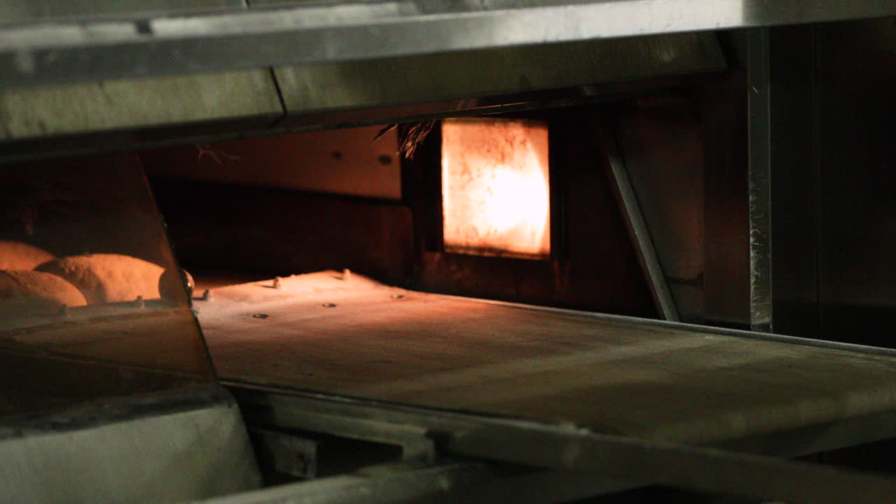 пекарь аккуратно ставит противень с хлебом в духовку для выпечки - замедленная съемка