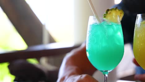 two vibrant cocktails clinked together in a bright, sunlit environment, capturing a moment of celebration and refreshment