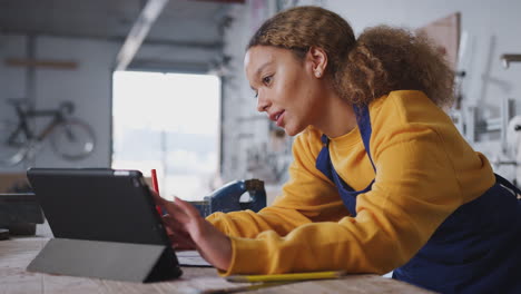 female business owner in workshop for building bicycles using digital tablet