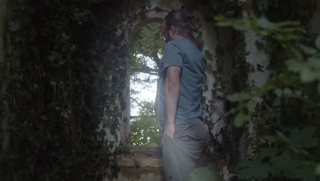 man stares through ivy-covered ancient church window, slow push