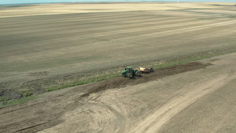 agriculture, beautiful aerial of tractor in open farm field with soil moving equipment