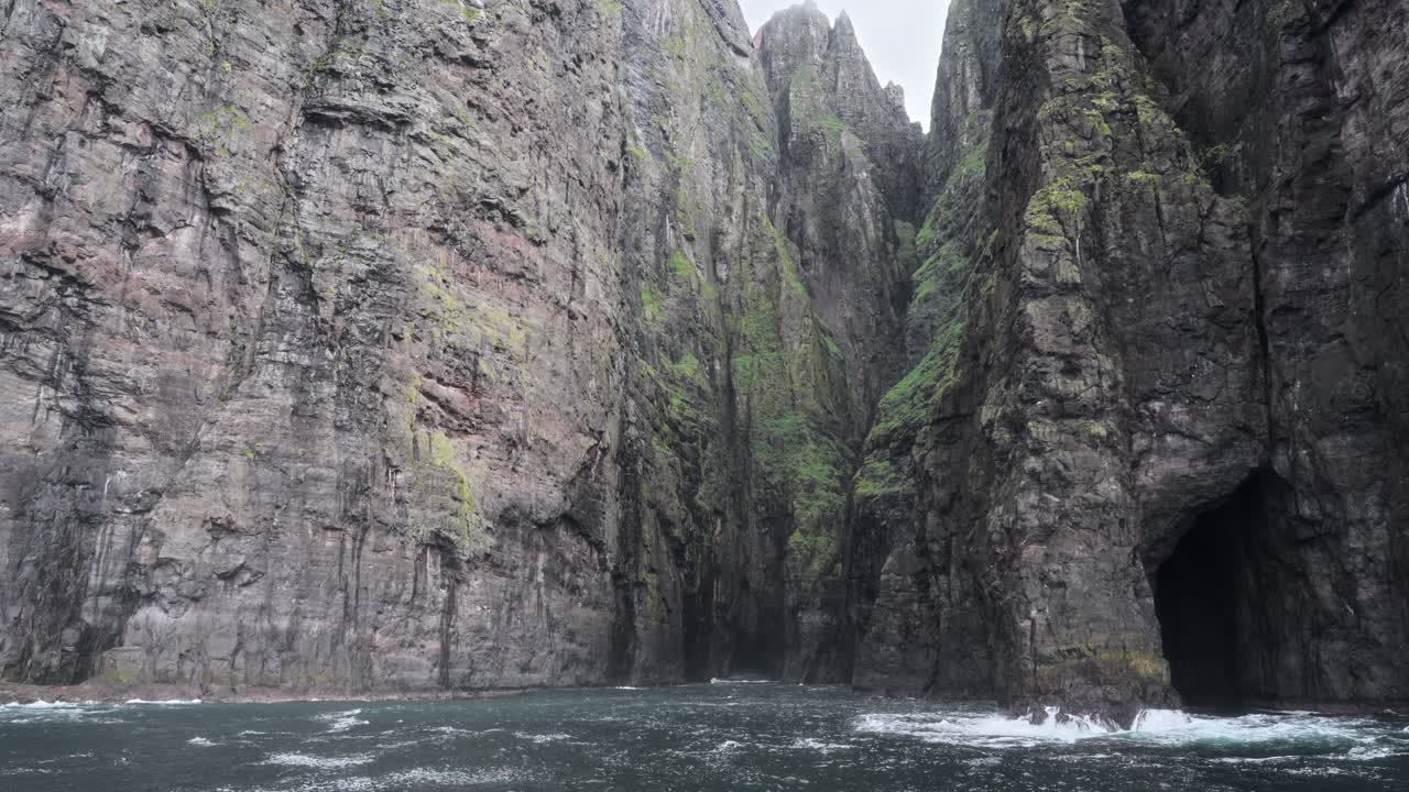Misty coastal cliffs with dramatic caves in Vestmannahavn, Faroe Islands
