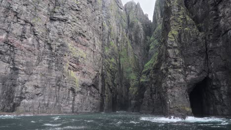 acantilados costeros brumosos con cuevas dramáticas en vestmannahavn, islas feroe