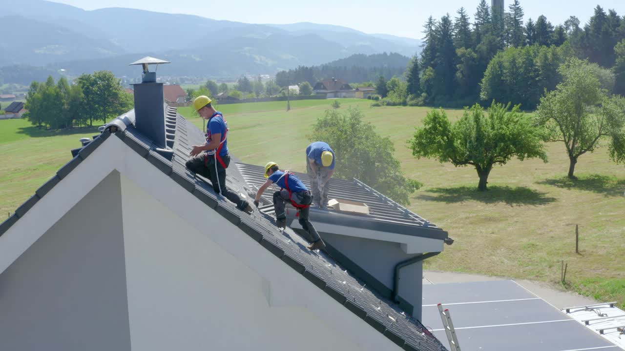Workers install solar panels on steep roof of house in Slovenia. Aerial