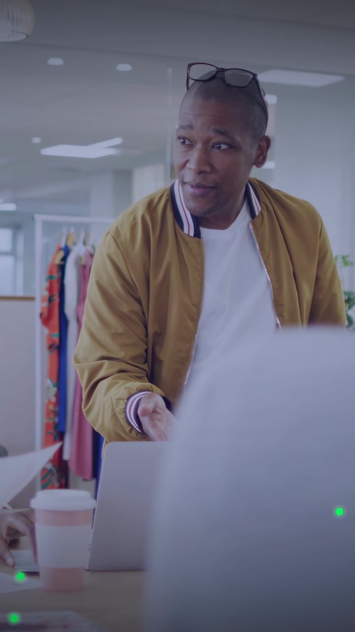 Vertical video: Man tapping laptop, causing green overlay and showing fashion design to colleague
