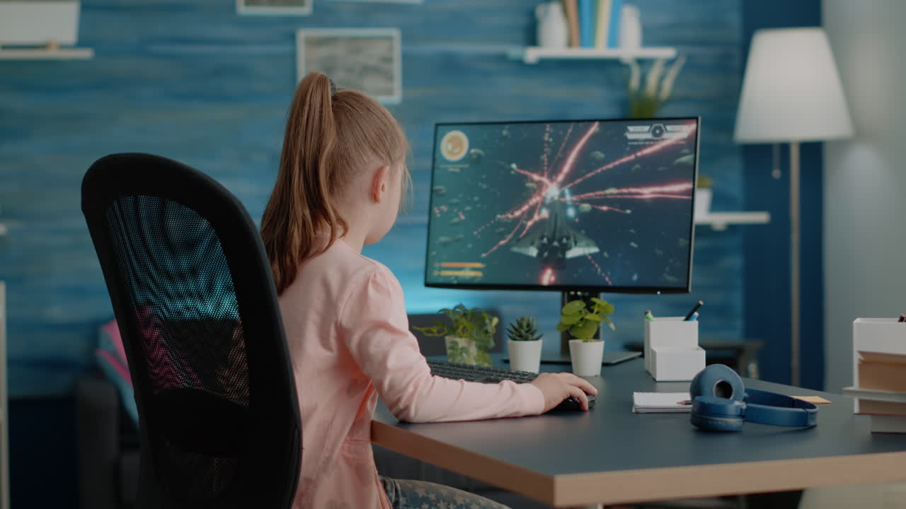 Young child playing action video games on computer at desk