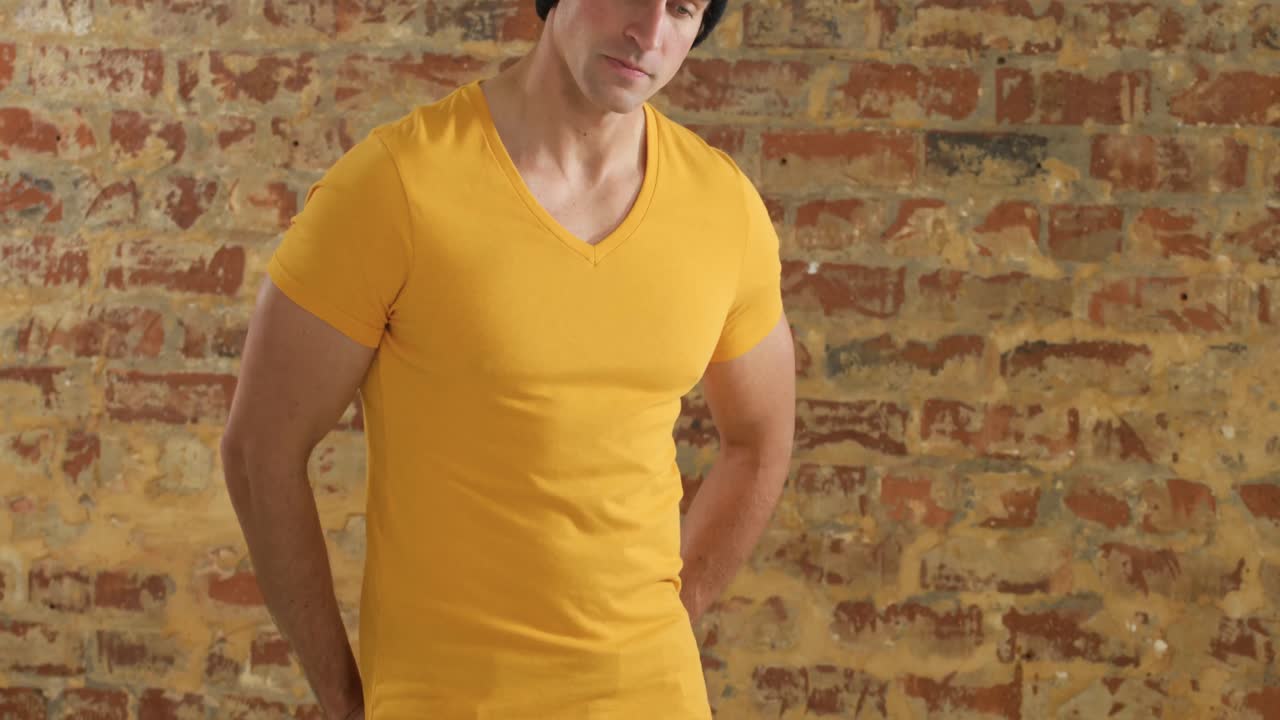 hombre caucásico mostrando su atuendo en una pared de ladrillo