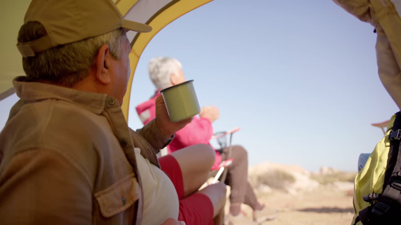 산에서 텐트에 누워서 커피를 마시며 느린 속도로 행복한 두 인종의 부부