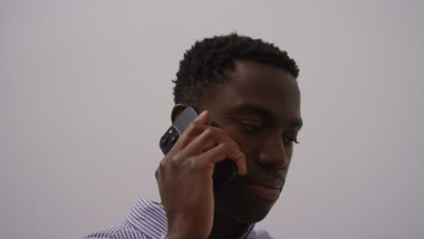 close up of young businessman in office talking on mobile phone looking frustrated and angry shot in real time