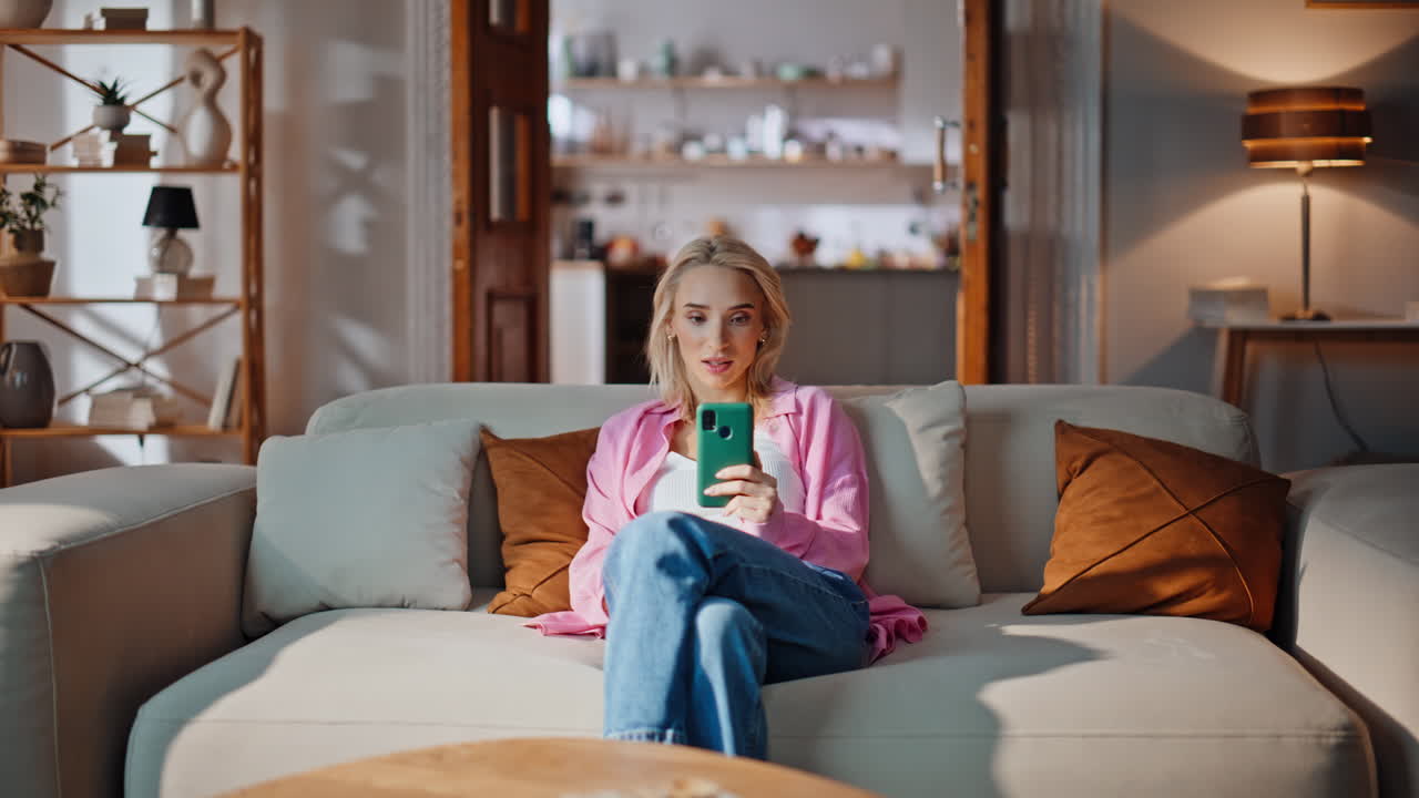 Happy lady shopping online using mobile phone at home sofa. Girl making purchase