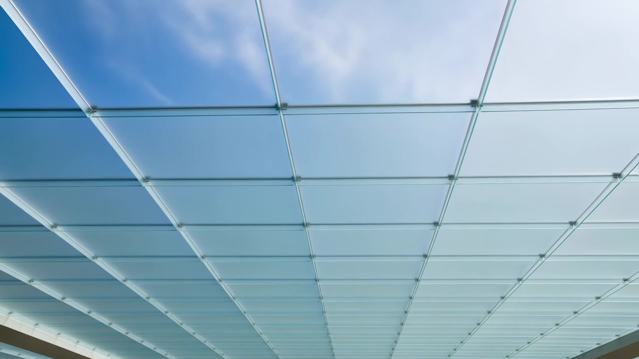 Low angle interior view of large frosted glass ceiling panels in metal grid, with circular fasteners at each intersection, soft diffuse glow, repeating square pattern, clean modern geometric structure