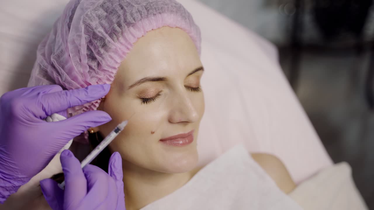 A beautiful woman is lying on the couch in the office of a beautician on the Botox procedure in the eye area. Beauty injections. Close-up.