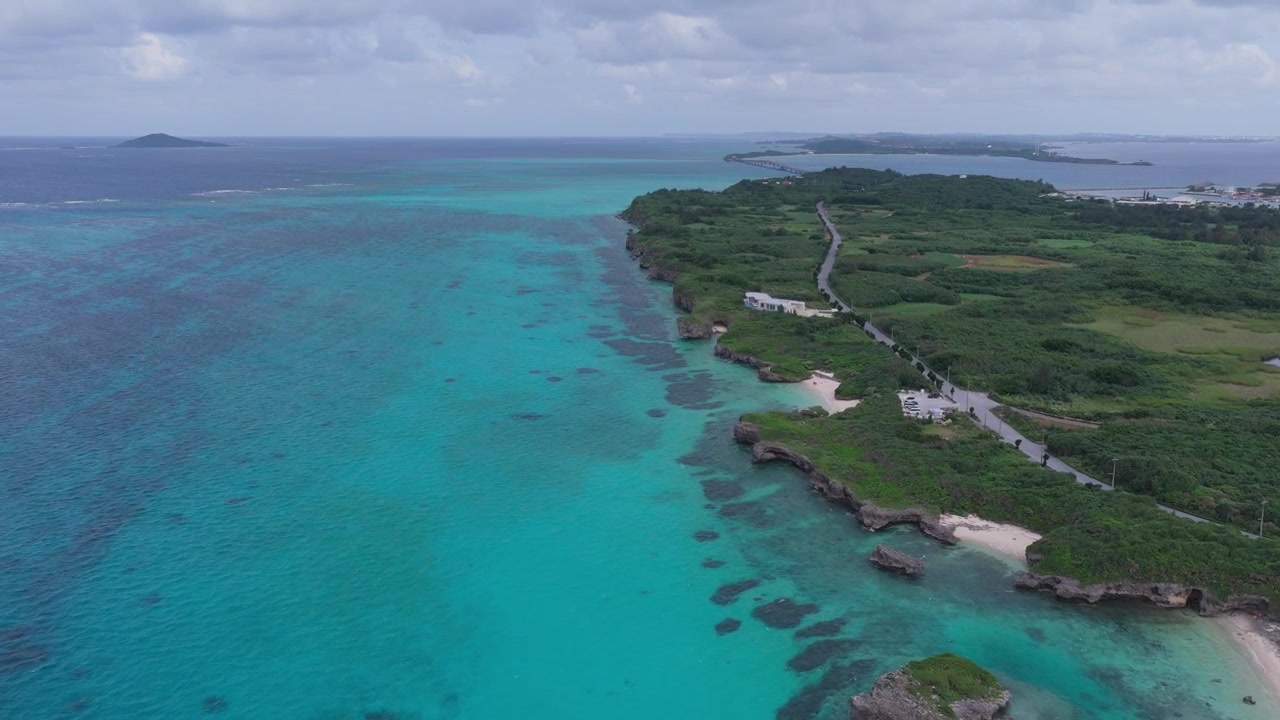 Riprese aeree orizzontali che si alzano e avanzano lungo la costa rocciosa e le acque turchesi dell'isola di Ikema, Miyakojima, Okinawa, Giappone.
