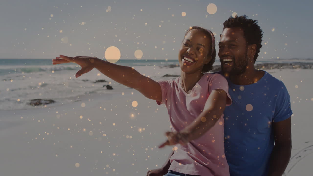 couple pointing toward ocean on sandy shoreline, with sparkle overlay highlighting travel marketing