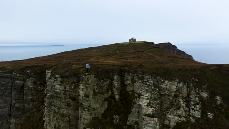 person running along cliff's edge of horn head, ireland - aerial tracking