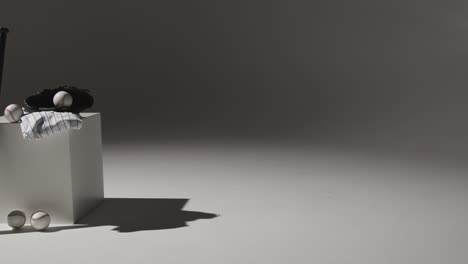 slow pan across studio baseball still life with bat ball catchers mitt and team jersey in low key lighting