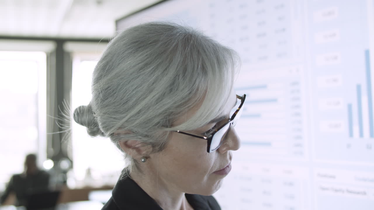 primer plano de una empresaria de contenido viendo una pantalla grande con gráficos