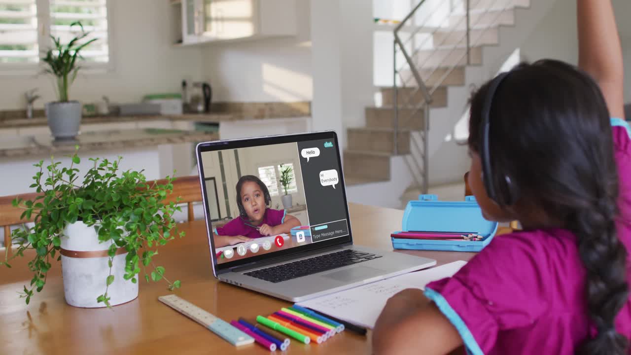 Schoolgirl using laptop for online lesson at home, with her school friend and web chat on screen