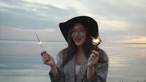 happy woman with sparkler at sunset