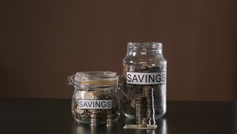 hand of man putting coin into glass with savings