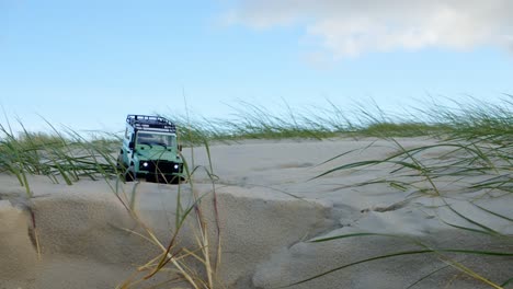 pequeño jeep rc conduciendo en dunas de playa de arena contra el cielo azul, vista estática