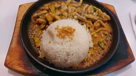 overhead view of sizzling bicol express and rice on a hot plate, a popular authentic traditional dish from the philippines