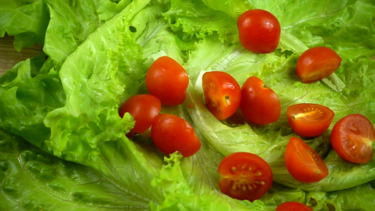 Falling of tomatoes on lettuce leaves. Slow motion