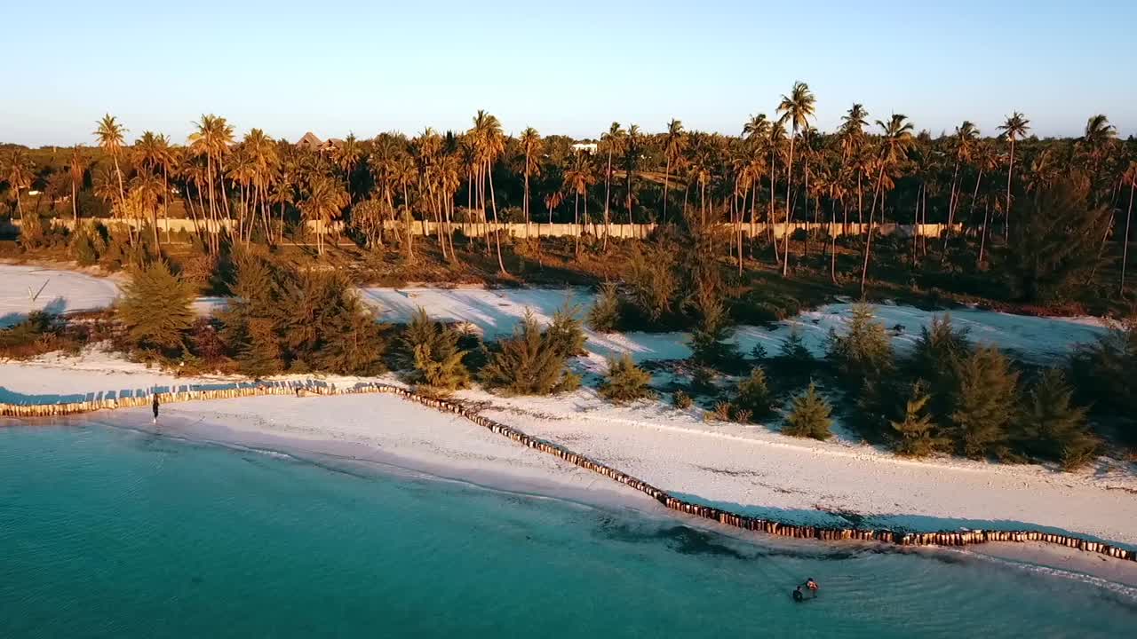긴 그림자와 함께 일몰에 꿈의 해변 앞에서 환상적인 비행 뒤로 드론 샷