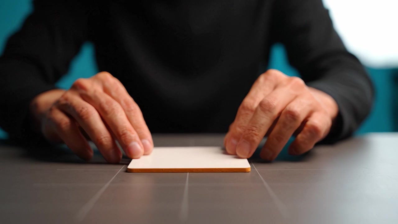 A Focused Moment: Hands Interacting with a Blank Surface as a Mysterious Object Lies in the Center of Attention on a Clean, Modern Table Amidst a Soft Background