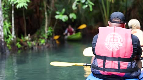 two people kayaking in a lush, tropical canal