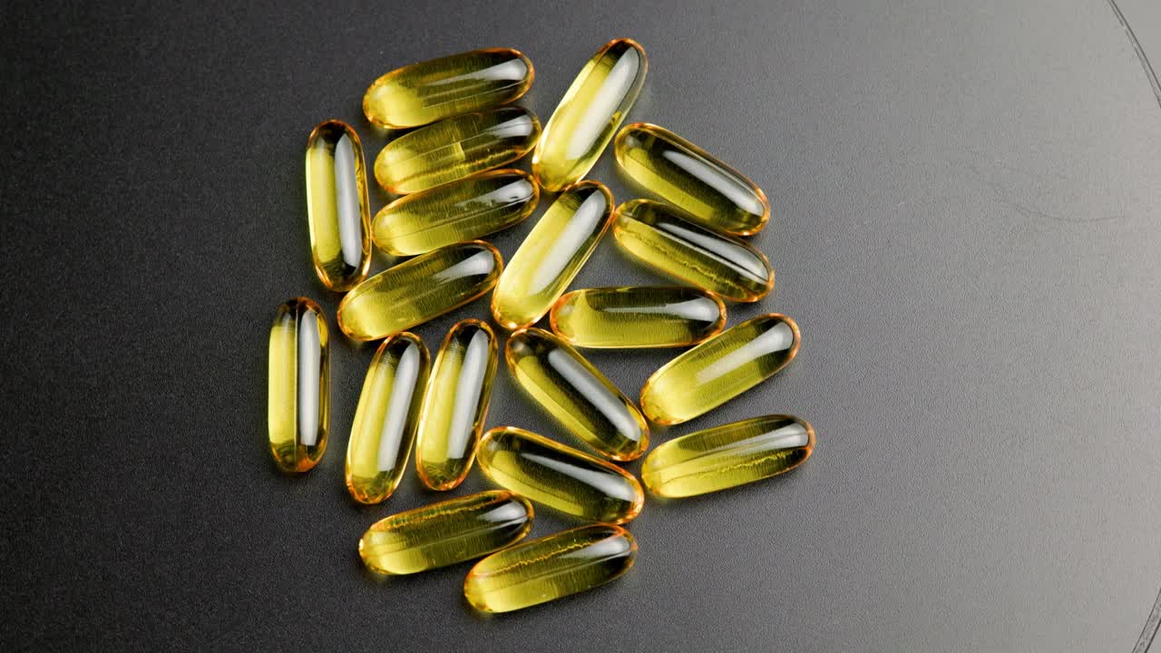 grupo de pastillas transparentes doradas con medicamento líquido girando en la superficie negra