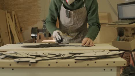 a worker paints a wooden product with a sponge. painting of plywood products made on a cnc laser machine