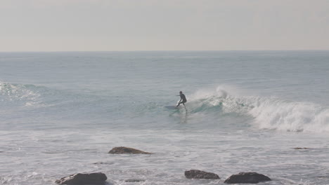 a surfer manages to catch a wave while another two wait for theirs in malibu california