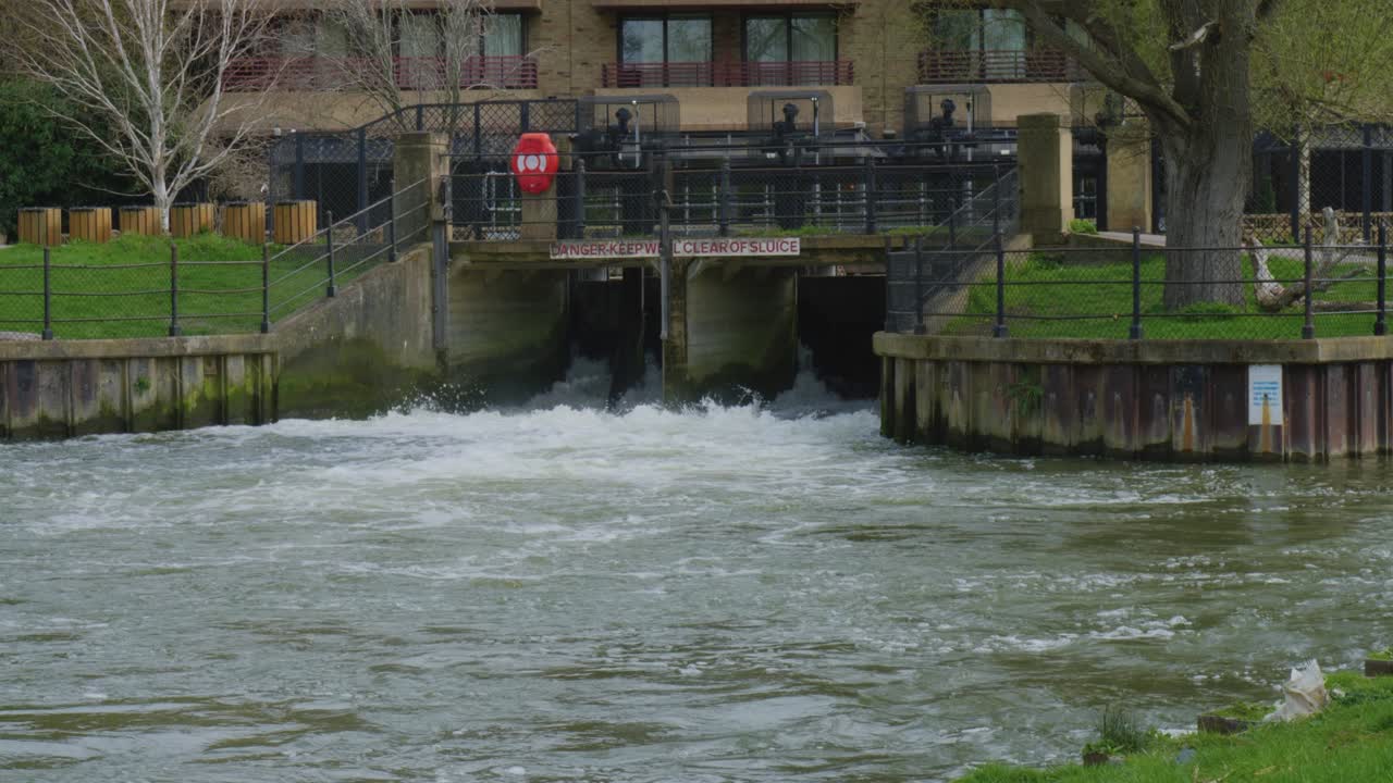 Water roars out of floodgates or sluice gates into river in Cambridge England