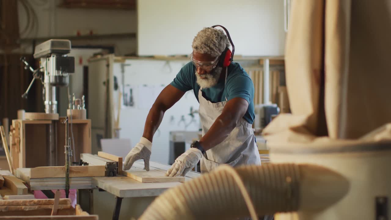 carpintero afroamericano que usa una sierra de mesa para cortar madera en una carpintería