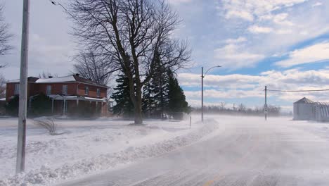 snowstorm in late winter - wind-blown snow above the ground in neighborhood in canada