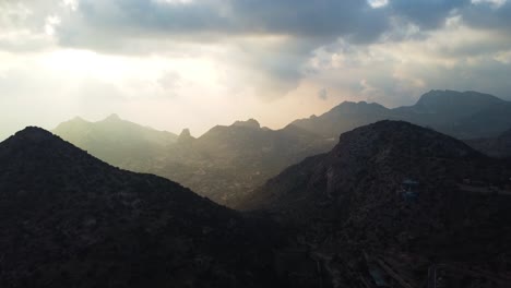 Antena-Que-Establece-La-Inclinación-De-Una-Hermosa-Cordillera-En-Arabia-Saudita-Iluminada-Por-Rayos-De-Sol-Entre-Las-Nubes