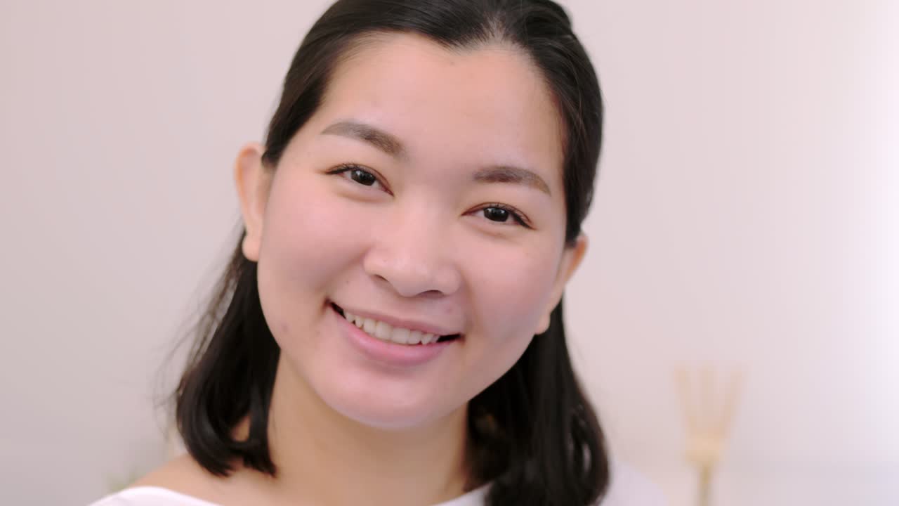 아름답고 웃고 있는 아시아 여성들은 휴일에 혼자 전문적인 초상화를 취한 카메라를 바라보며 극도로 자신감 있는 젊은 얼굴을 하고 맑은 빛, 슬로우 모션 장면으로 휴식을 취합니다.