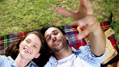 pareja interactuando entre sí mientras yacen en una manta de picnic