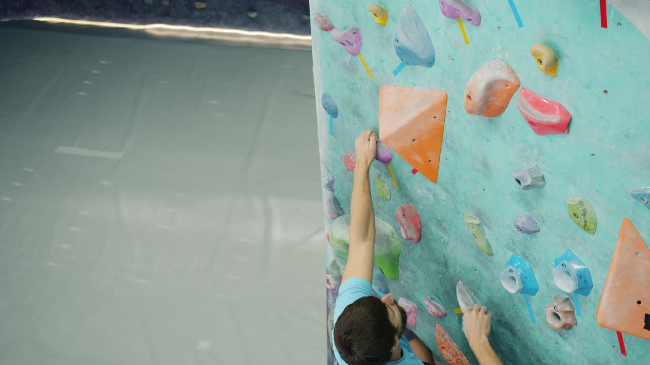 человек поднимается на скалу на скалолазающей стене