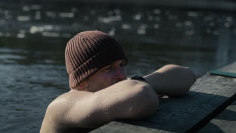 Caucasian-adult-man-checking-parameters-on-the-smartwatch-while-swimming-in-frozen-lake.