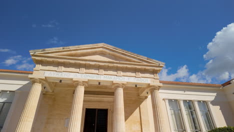 un edificio neoclásico con grandes columnas y un techo de azulejos rojos en pafos