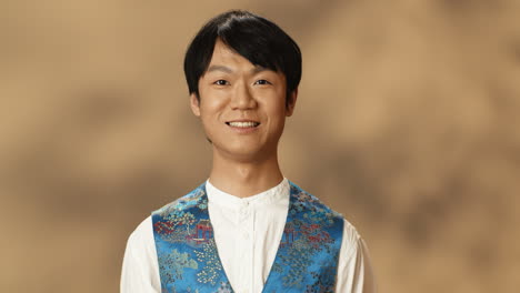 portrait of young asian man in traditional clothes opening eyes and smiling cheerfully at camera