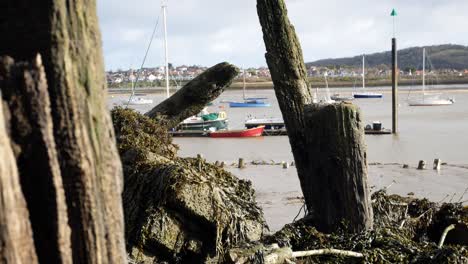 rotten derelict old pier wood debris on conwy harbour waterfront close up dolly left shot