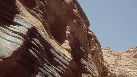 pan right close up shot of a large textured colorful desert sandstone rock wall being hit by the sun in the buckskin gulch slot canyon in southern utah near arizona on a warm sunny spring morning