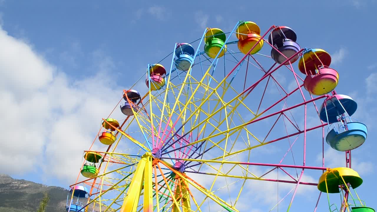 big wheel with multicolored cabins in amusement park