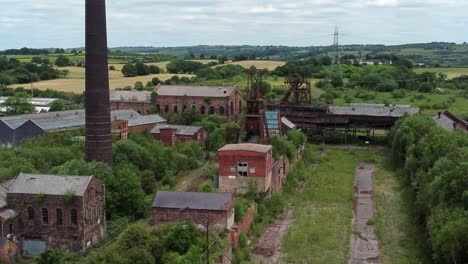 abandonada antigua mina de carbón cubierta de maleza edificios de museos industriales vista aérea reversa a la derecha