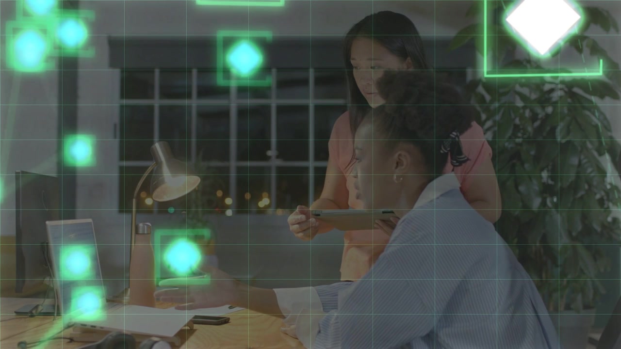 Seated woman tapping pad causing green overlays standing colleague leaning reviewing tech data