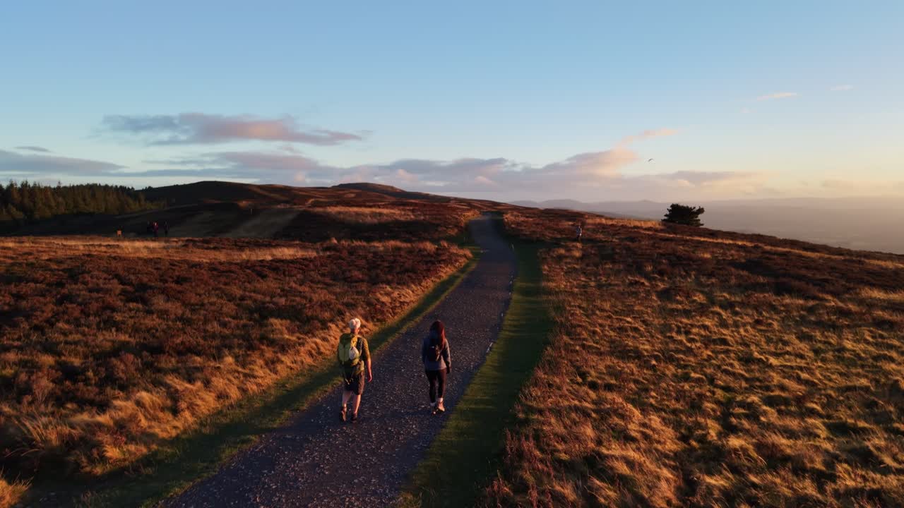 Hikers walking the Moel Famau trail at sunset in slow motion in stunning HDR, North Wales, UK