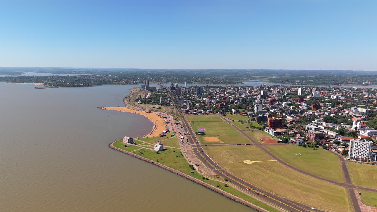 Aerial shot of San José beach, Encarnación, Paraguay. Overflight over the city on the slopes of the Paraná River with its streets and buildings on a bright sunny day.